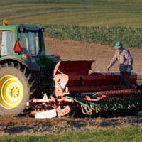 lawn mower attached to the back of a tractor with worker nearby