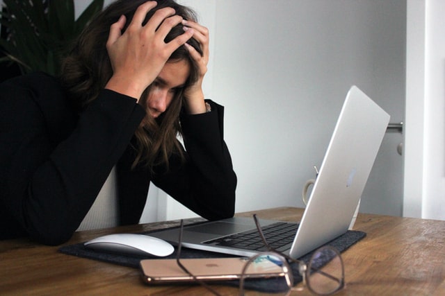 a stressed out female office worker with her head in her hands