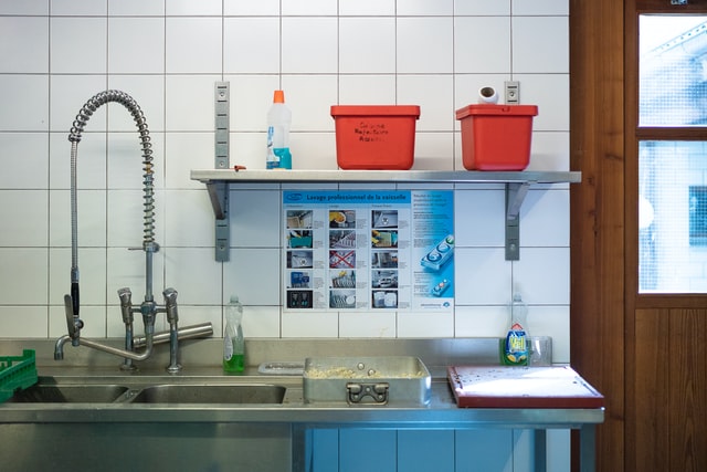 A commercial kitchen with food safety notices and cleaning products clearly displayed