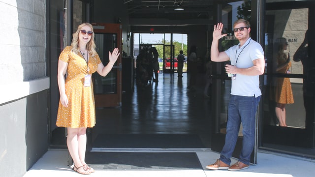 Two workers standing at a doorway greeting customers